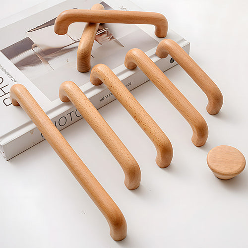 Beech wood cabinet handles and knobs full range arranged on a pale surface
